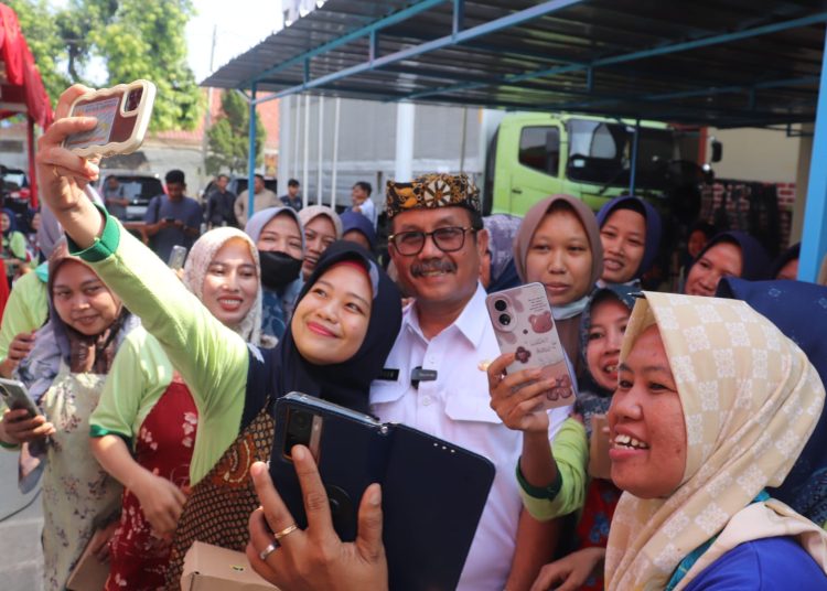 Bupati Cirebon, Imron (tengah) melakukan swafoto bersama sejumlah pekerja pabrik rokok usai penyaluran BLT dari dana DBHCHT di PT Sinar Grage Jaya, Desa Kesugengan Lor, Kecamatan Depok, Kabupaten Cirebon, Rabu (22/11/2023).