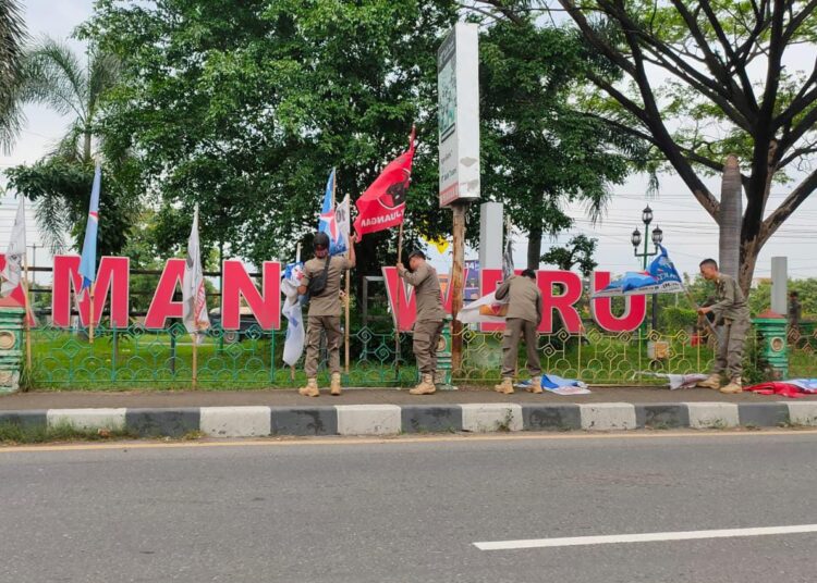 Personel dari Satpol PP dan Bawaslu Kabupaten Cirebon, saat menertibkan APK dan baliho di sepanjang jalan Pantura Cirebon yang dinilai asal pasang dan membahayakan pengendara, Selasa (23/1/2024).