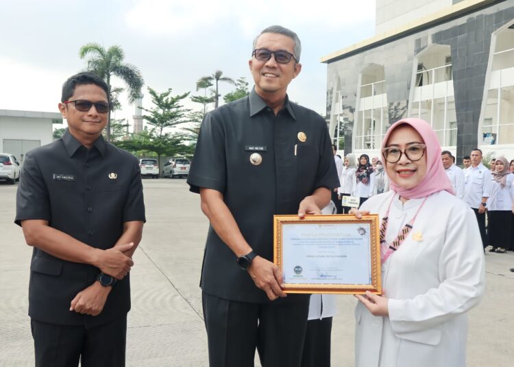 Pj. Wali Kota Cirebon H. Agus Mulyadi didampingi Pj. Sekda Arif Kurniawan menyerahkan piagam Penghargaan Penganugerahan Predikat Penilaian Kepatuhan Penyelenggaraan Pelayanan Publik Tahun 2023 dari Ombudsman Republik Indonesia dalam apel pagi di halaman Balaikota Cirebon, Rabu (24/1/2024).* Foto: Pemkot Cirebon