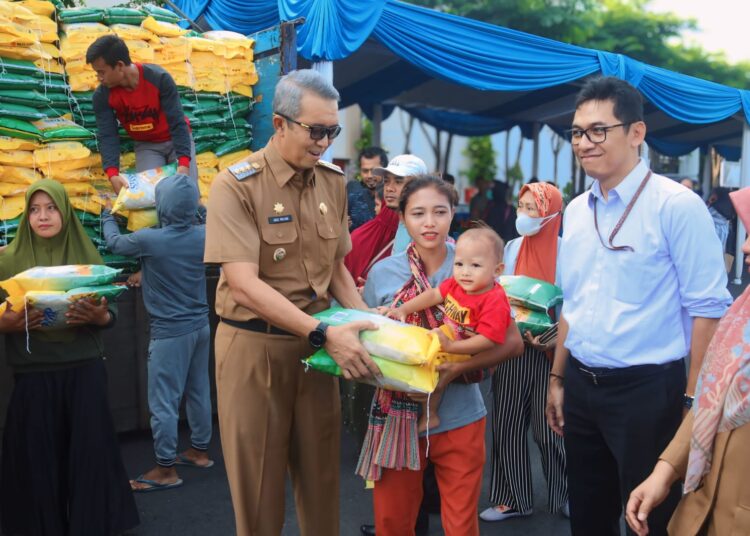 Pj Wali Kota H Agus Mulyadi menyerahkan beras saat Gerakan Pangan Murah di halaman parkir GCM, Senin (25/3/2024).*