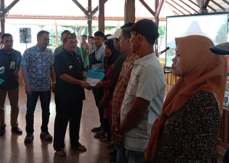 Bupati Cirebon, Imron, didampingi Kadisnaker Novi Hendrianto, saat menyerahkan bantuan bagi keluarga PMI yang mengalami masalah dari yang sakit hingga meninggal dunia, di Pendopo Bupati, Jumat (3/4/2024).