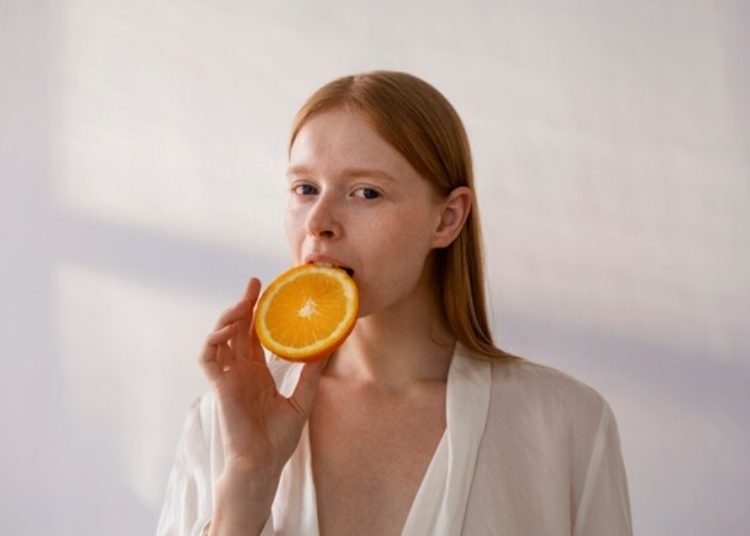 Ilustrasi seseorang memakan jeruk yang banyak mengandung vitamin C. Foto: Freepik